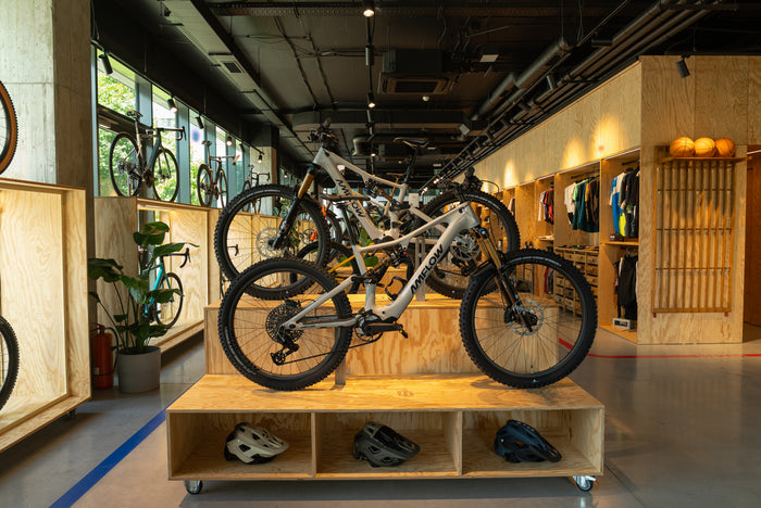 Elektrobicykle a prilby v cyklopredajni Velocity, nad nimi čierny strop s rozvodmi vzduchotechniky